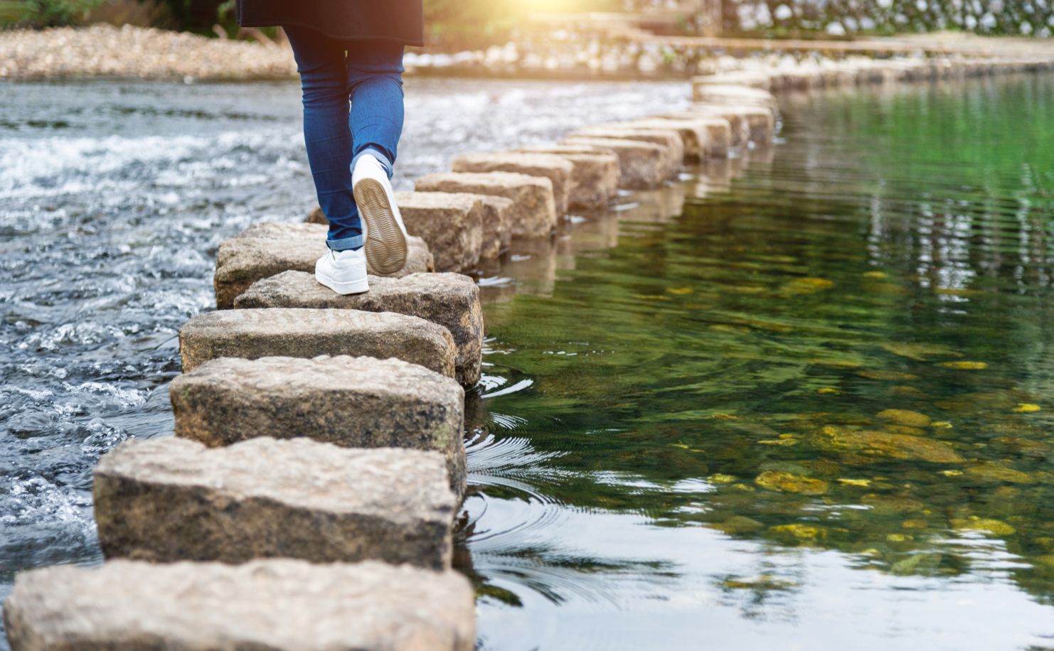 Woman crossing a river on stepping stones